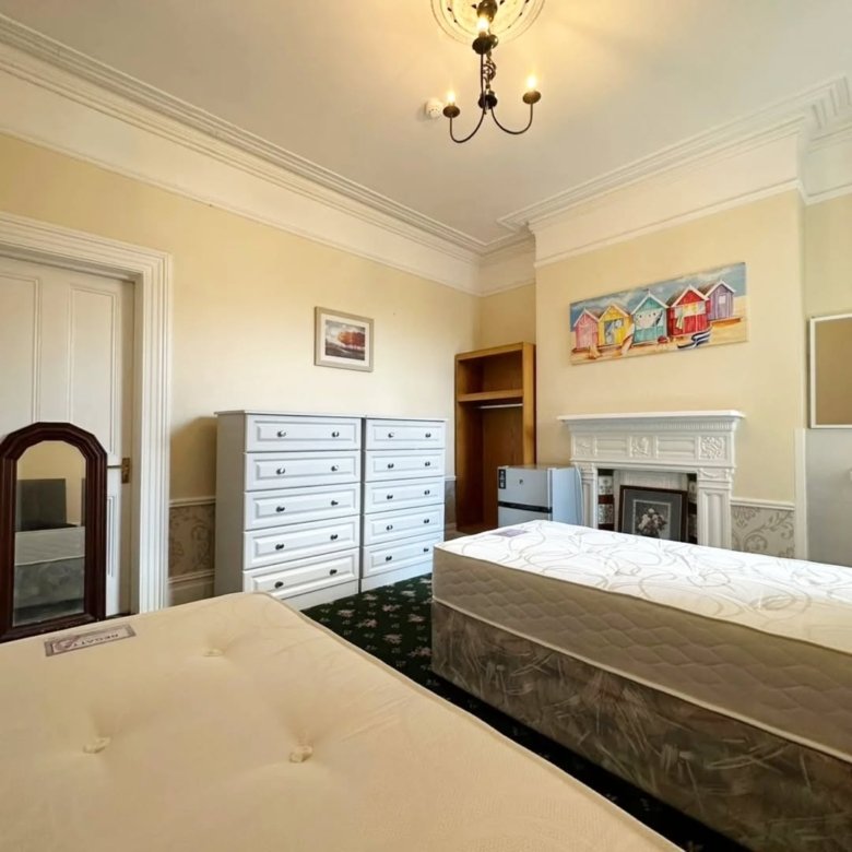 Bedroom with two beds, white dressers, and beach hut art.