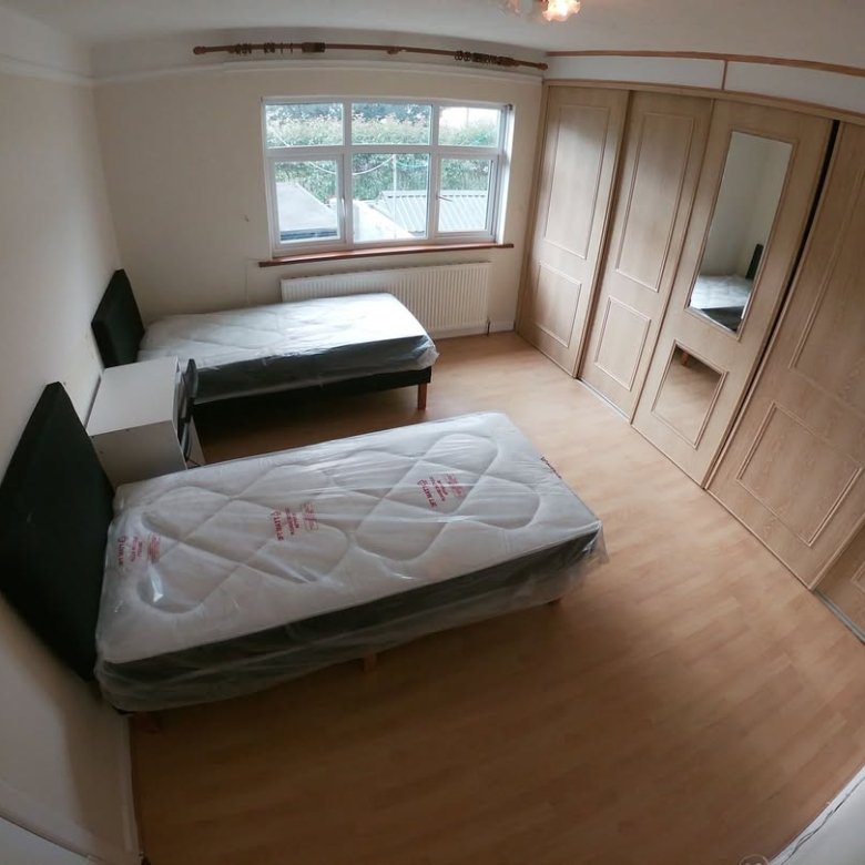 Bedroom with two beds, wardrobe, and window with natural light.