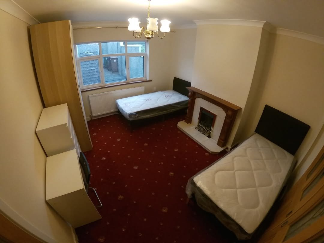 Bedroom with two single beds, fireplace, wardrobe, and red carpet.