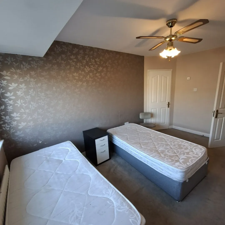 Bedroom with two single beds, nightstand, and ceiling fan.