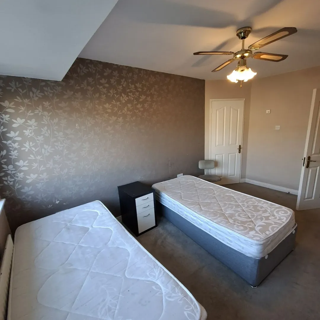 Bedroom with two single beds, nightstand, and ceiling fan.