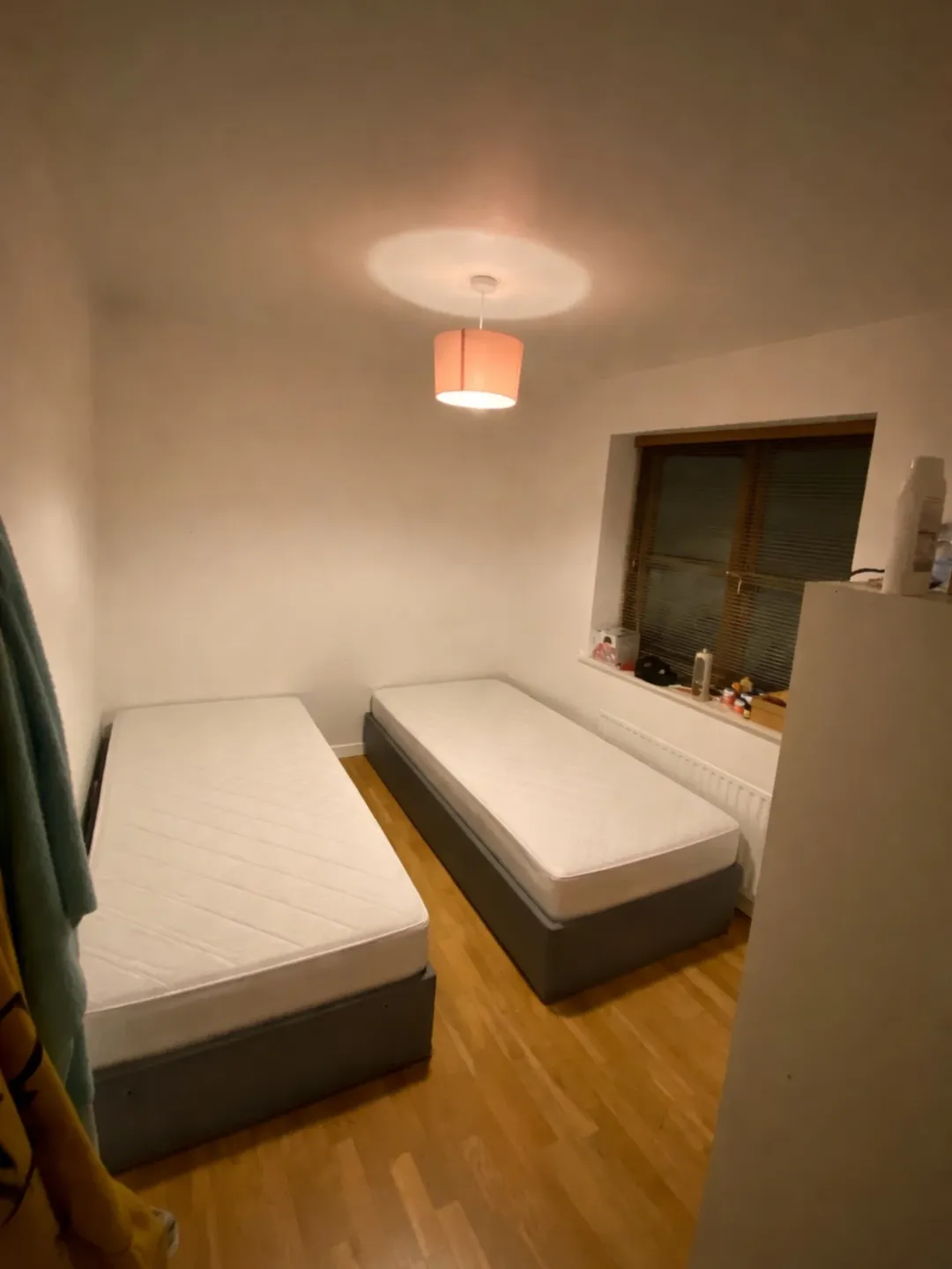 Cozy bedroom with two single beds, light wood floor, and warm lighting.