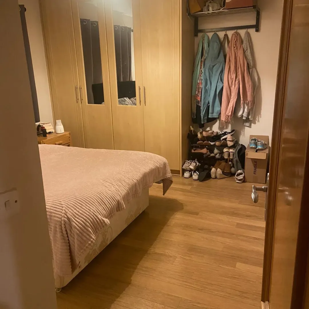 Bedroom with bed, wardrobe, and shoe rack. Light wood flooring.