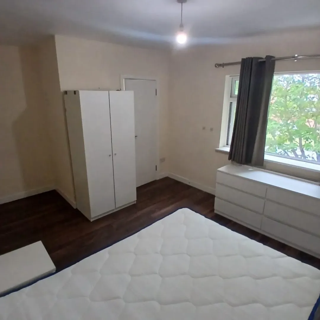 Bedroom with white furniture, dark wood floor, and a window.