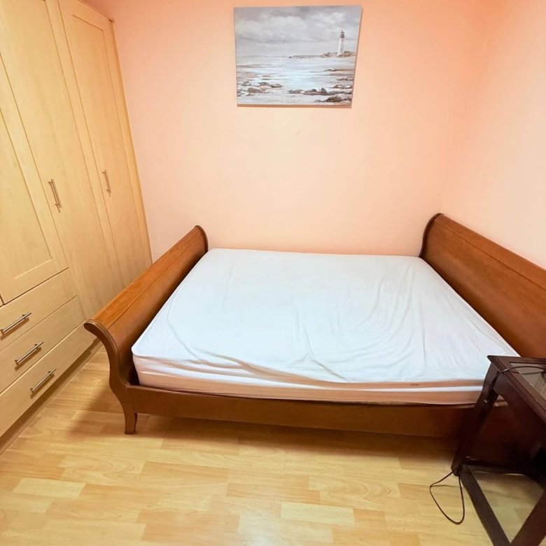 Bedroom with wooden bed, wardrobe, and seascape painting above the bed.