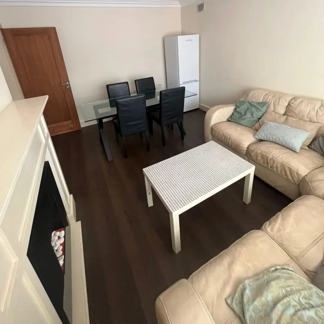 Living room with beige sofa, glass dining table, white coffee table, and fireplace.