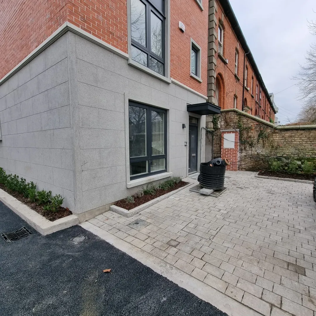 Modern brick and stone building exterior with gray window frames and paved driveway.