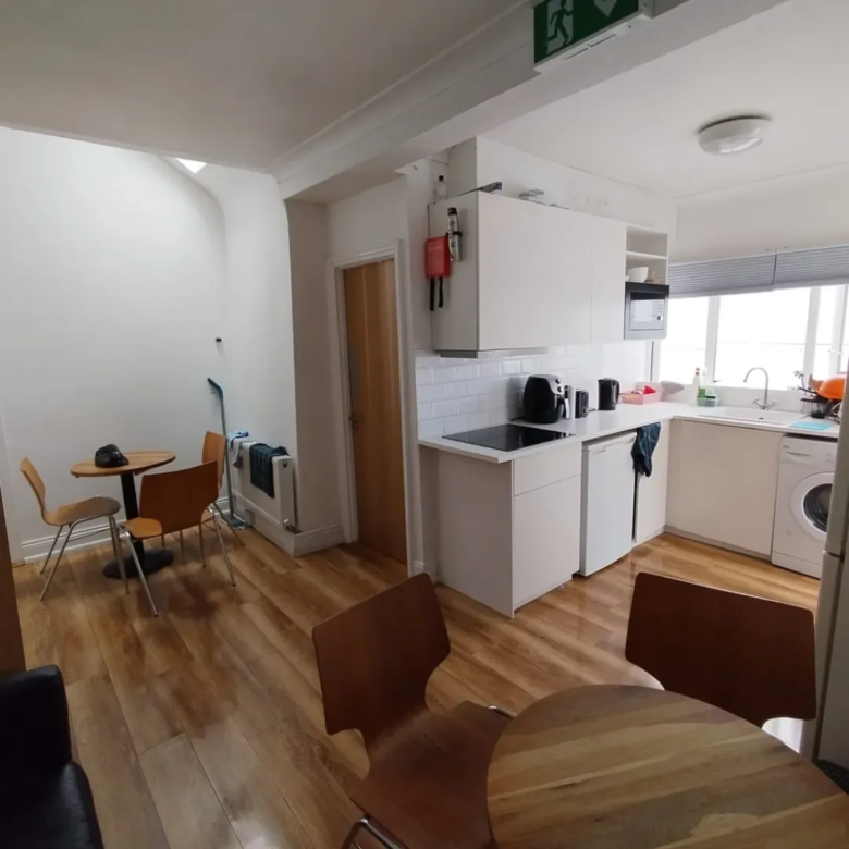 Bright kitchen with white cabinets, wooden floors, and dining area.