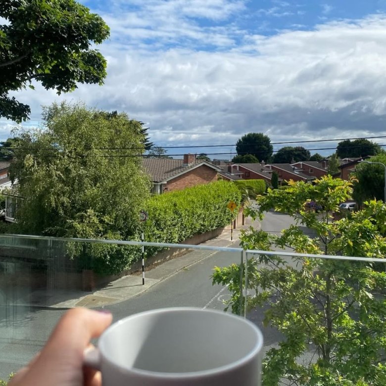Coffee cup view: suburban street, houses, and cloudy sky.