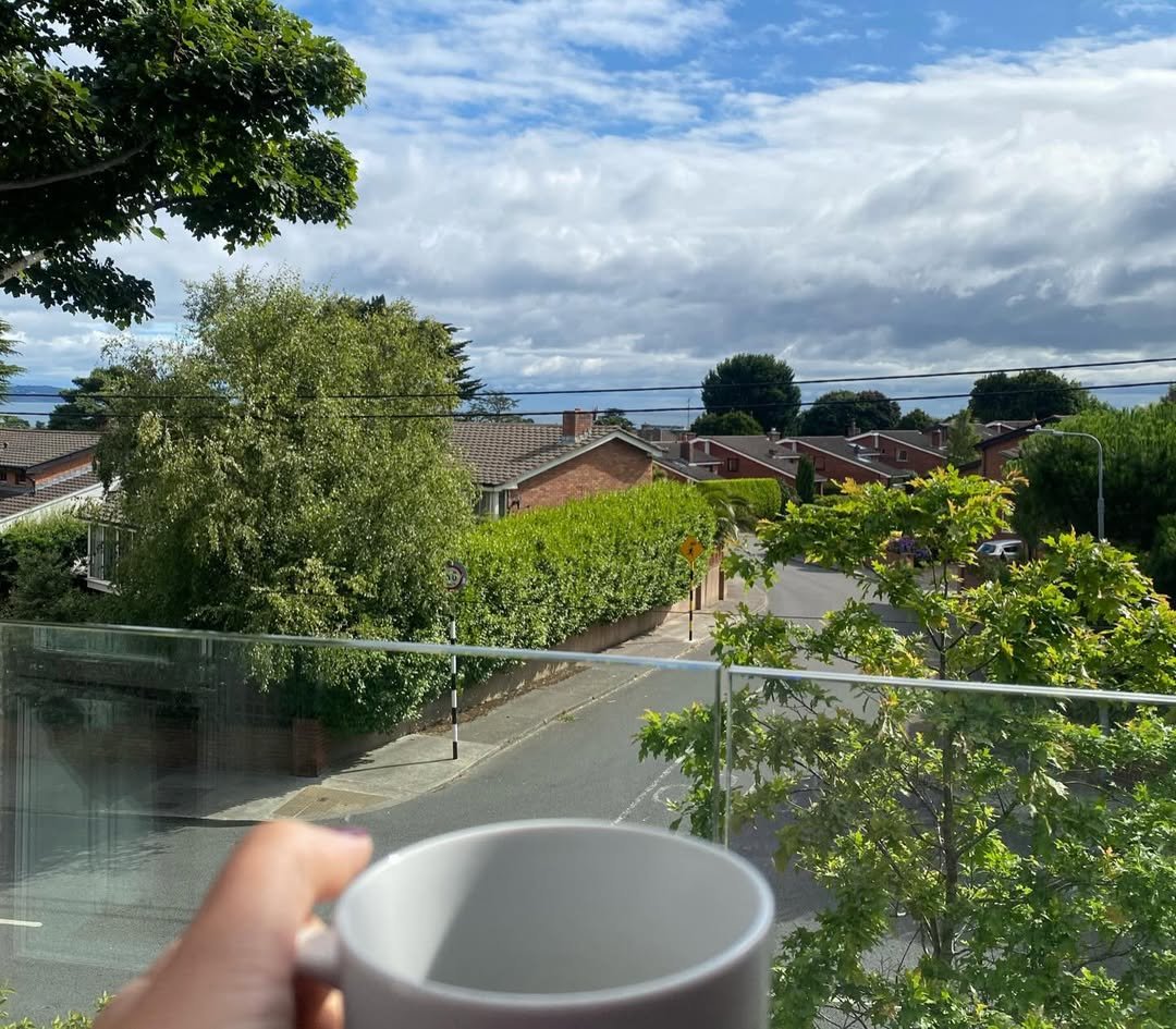Coffee cup view: suburban street, houses, and cloudy sky.