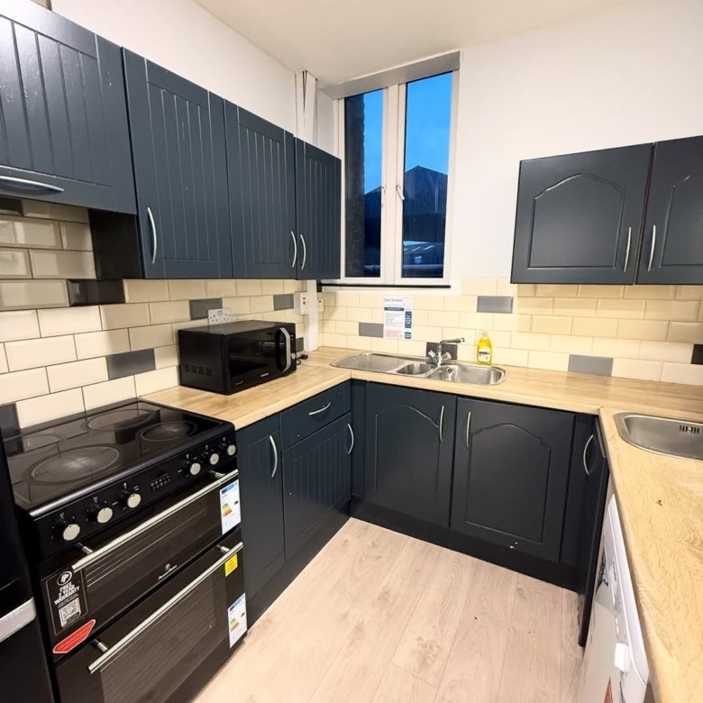 Compact kitchen with dark blue cabinets, light wood countertops, and modern appliances.