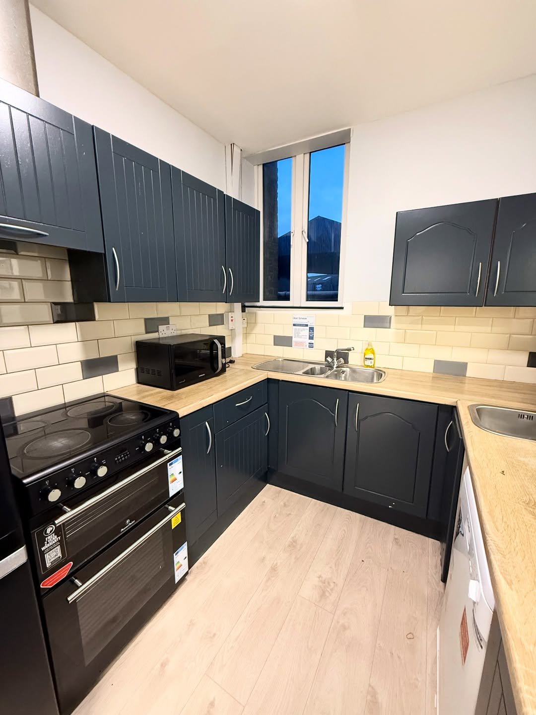Compact kitchen with dark blue cabinets, light wood countertops, and modern appliances.
