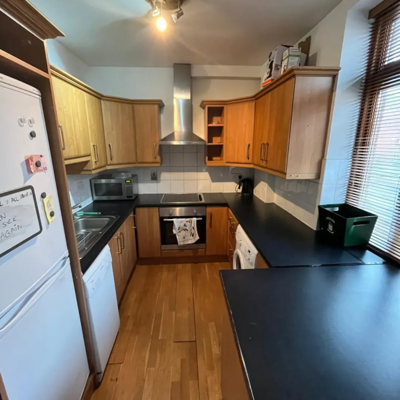 Compact kitchen with wood cabinets, black countertops, and white appliances.