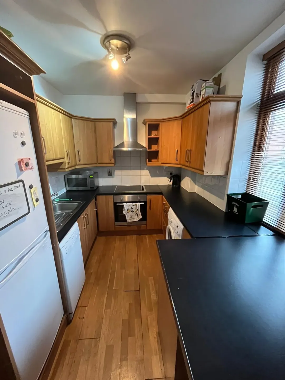 Compact kitchen with wood cabinets, black countertops, and white appliances.