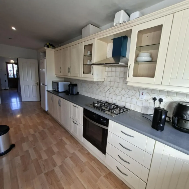Cream kitchen with gas hob, oven, and tiled backsplash. Neutral color scheme.