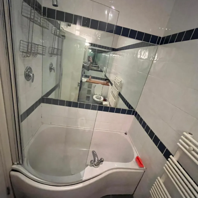 Bathroom with curved bathtub, glass shower screen, and towel warmer.