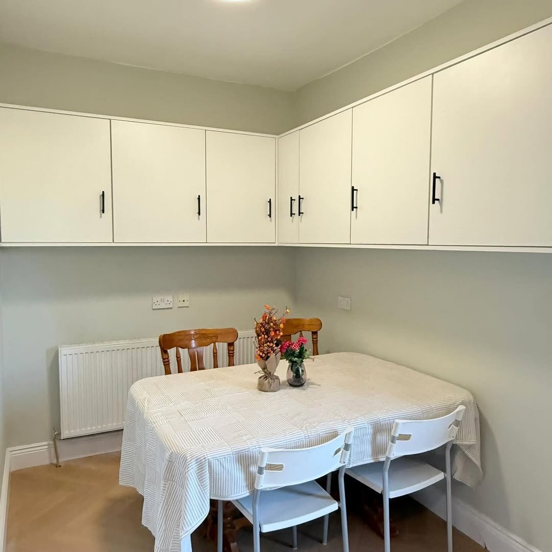 Dining area with white cabinets, table, and chairs. Neutral tones, simple decor.