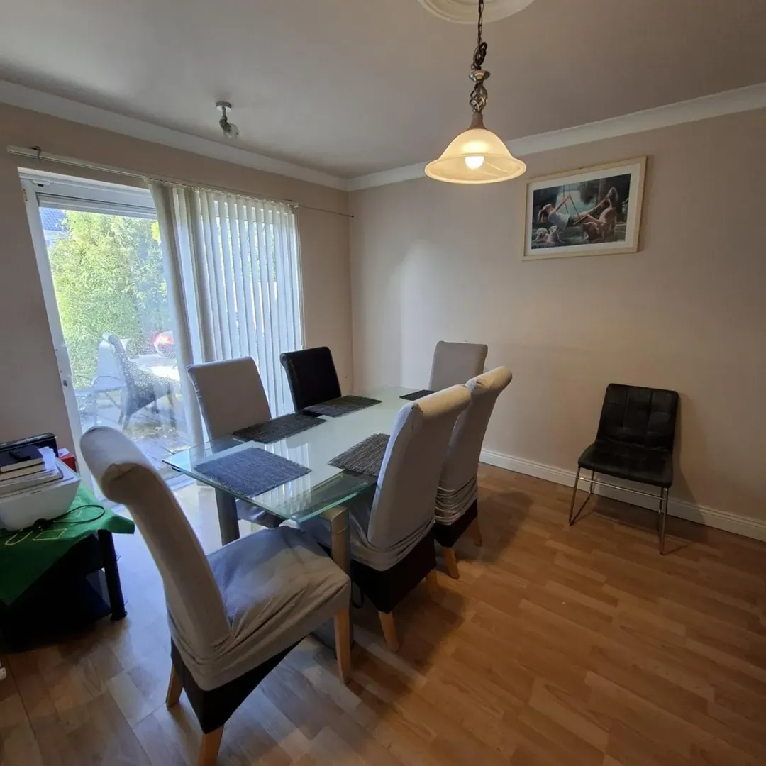 Dining room with glass table, upholstered chairs, and light wood floors.