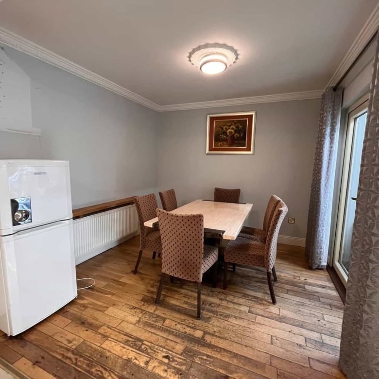 Dining room with table, chairs, fridge, and wall art in a home interior setting.