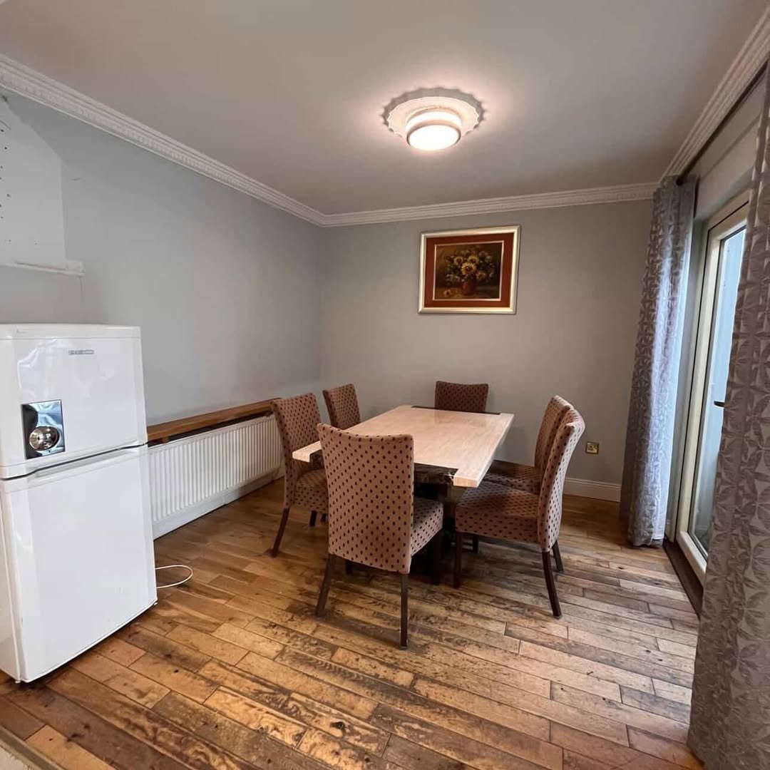 Dining room with table, chairs, fridge, and wall art in a home interior setting.