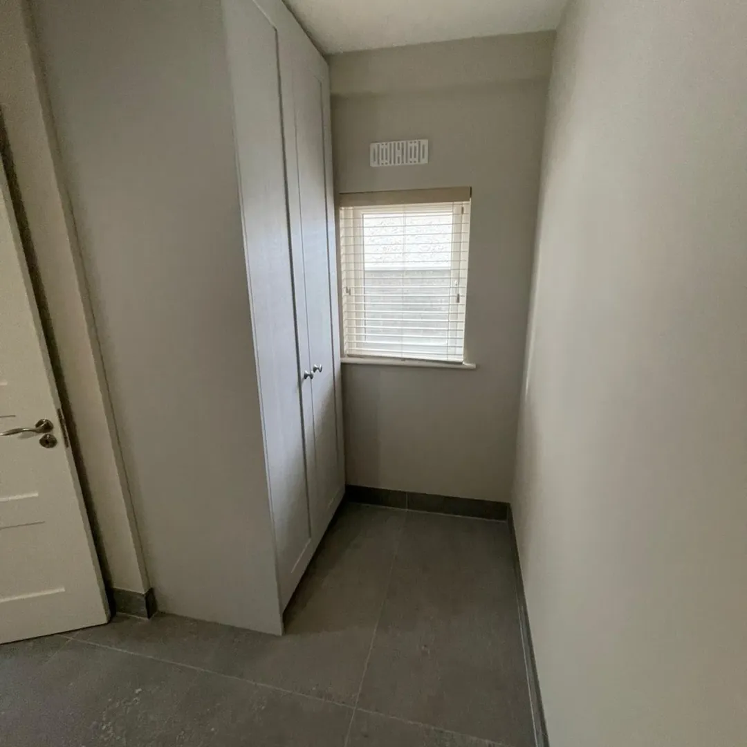 Gray closet next to a window with blinds in a small room.