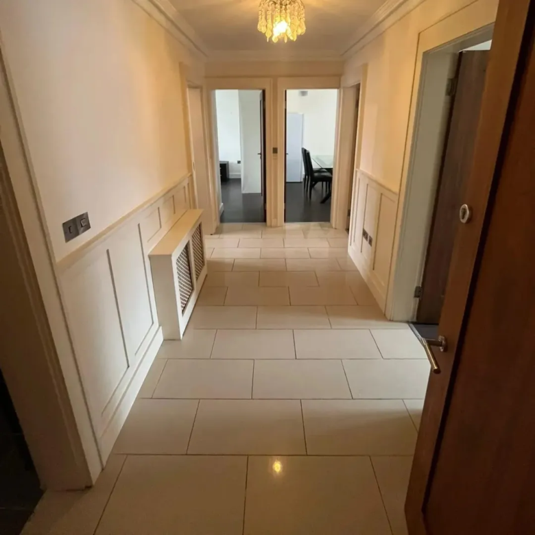 Hallway with cream tile floor and white wainscoting, neutral interior.