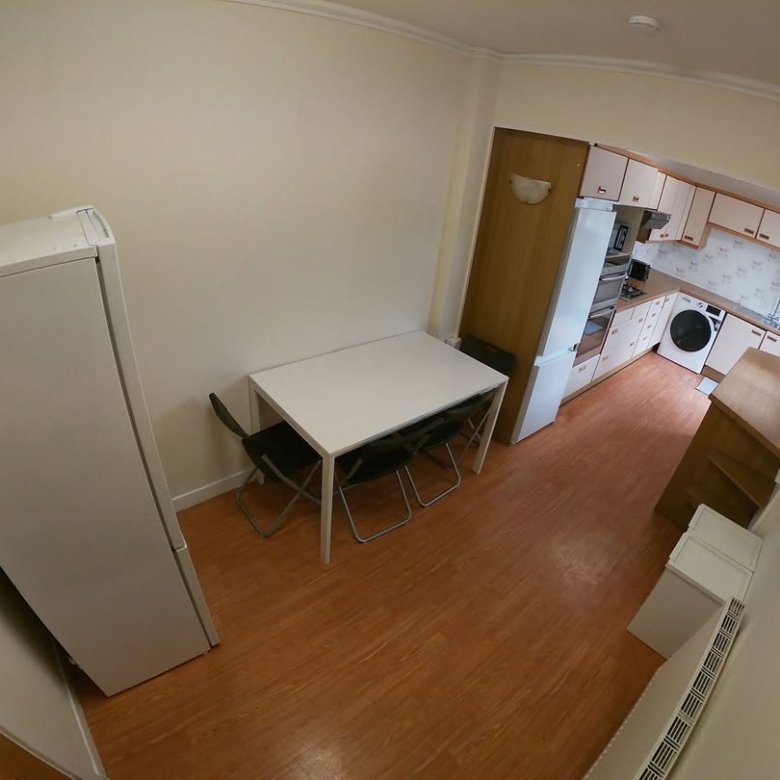 Kitchen dining area with table, chairs, fridge, and washing machine.