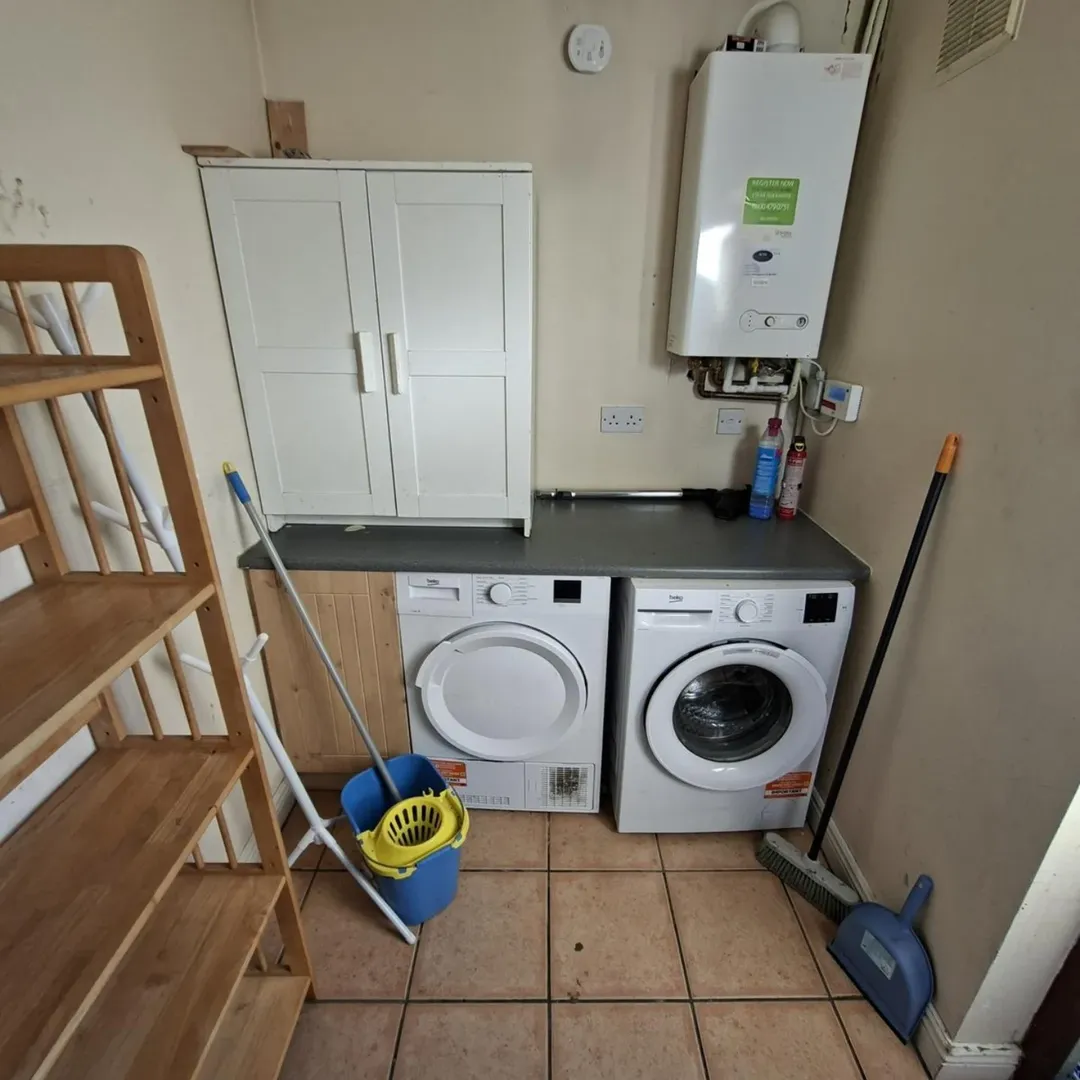 Laundry room with washer, dryer, cabinet, and cleaning supplies.