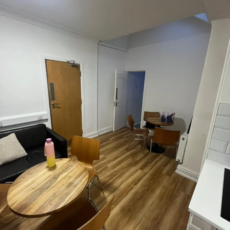 Living area with sofa, table, chairs, and doorway.