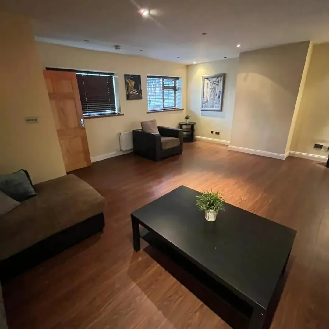 Living room with brown sofa, armchair, coffee table, and dark wood floors.