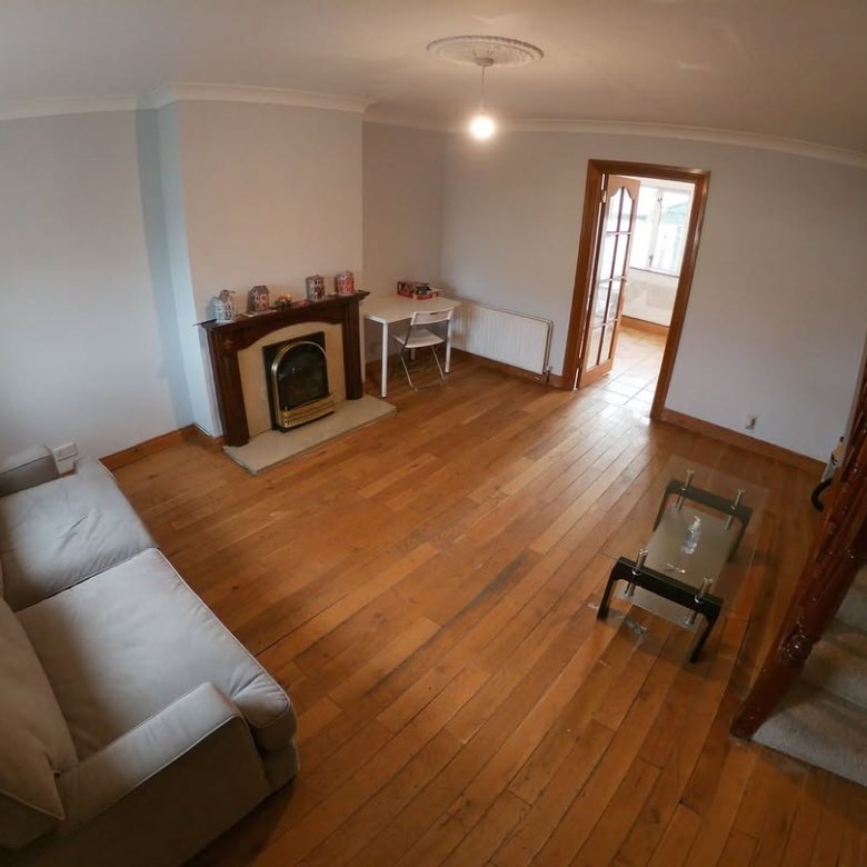 Living room with fireplace, sofa, table, and stairs. Hardwood floor.