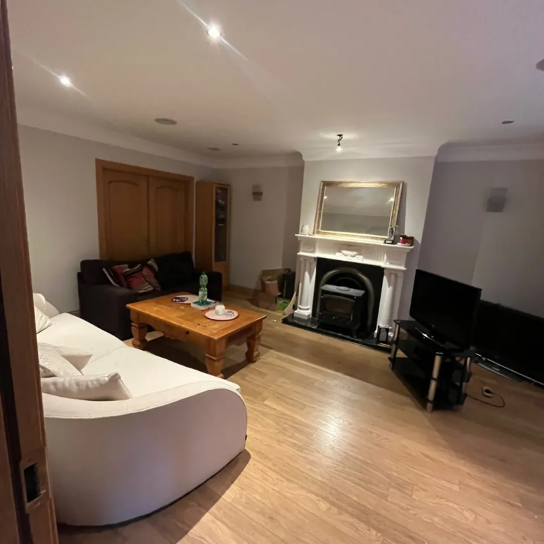 Living room with fireplace, wood floors, white sofa, and dark brown couch.