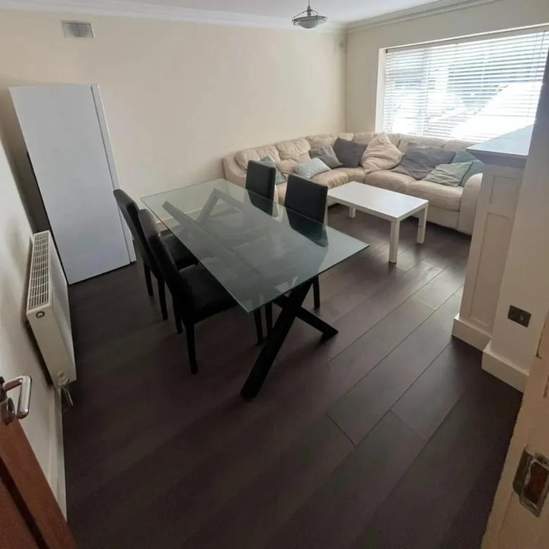 Living room with glass dining table, leather chairs, and sectional sofa.
