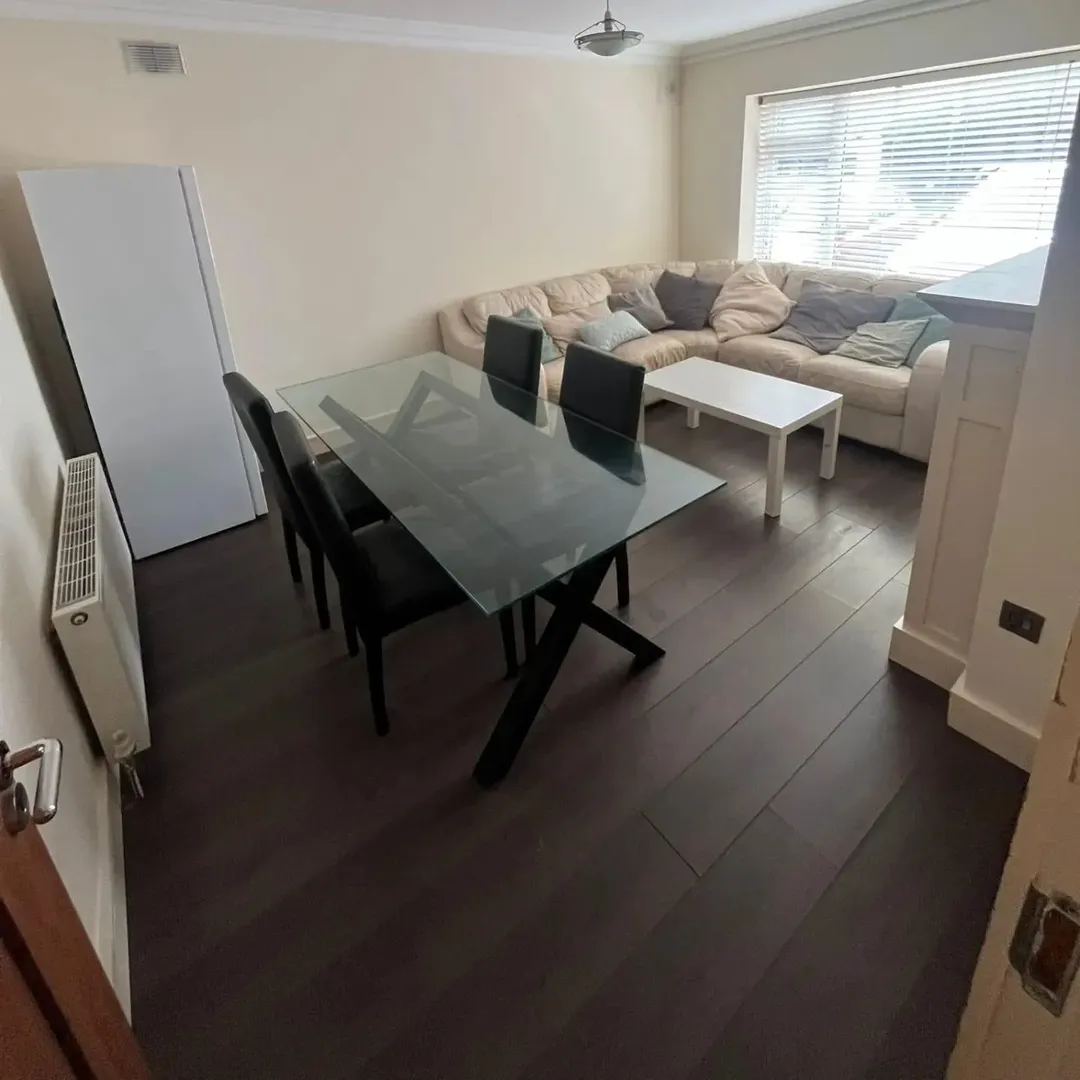 Living room with glass dining table, leather chairs, and sectional sofa.