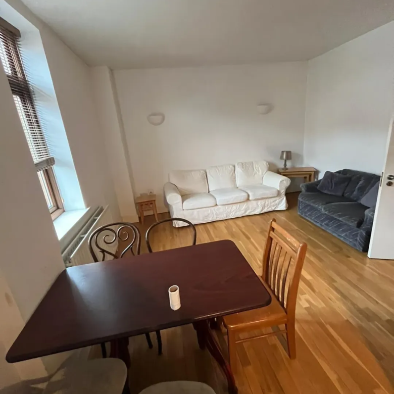 Living room with white sofa, gray loveseat, wood table and chairs, and window.