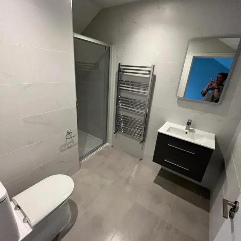 Modern bathroom with shower, toilet, sink, and heated towel rack.