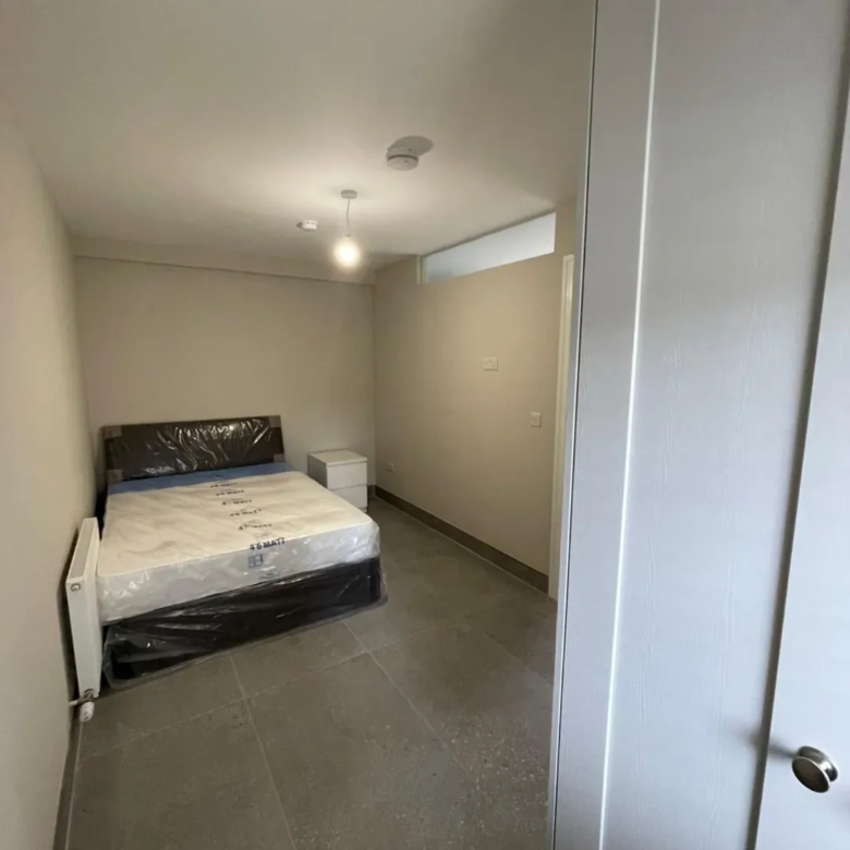 Modern bedroom interior with bed, radiator, and bedside table.
