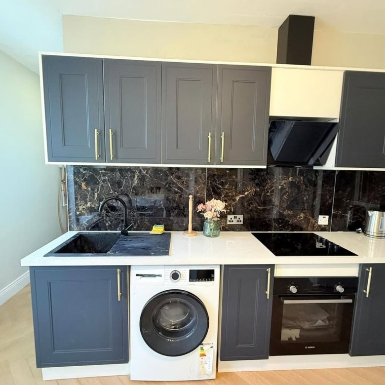 Modern kitchen with gray cabinets, black marble backsplash, and integrated appliances.