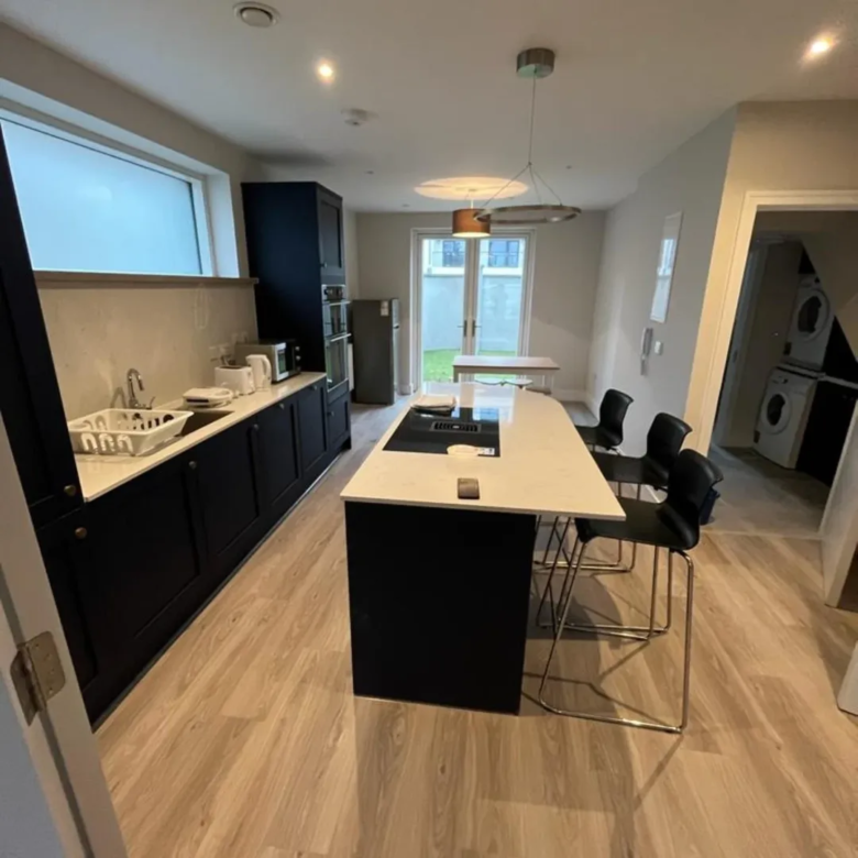 Modern kitchen with black cabinets, island, and laundry area.