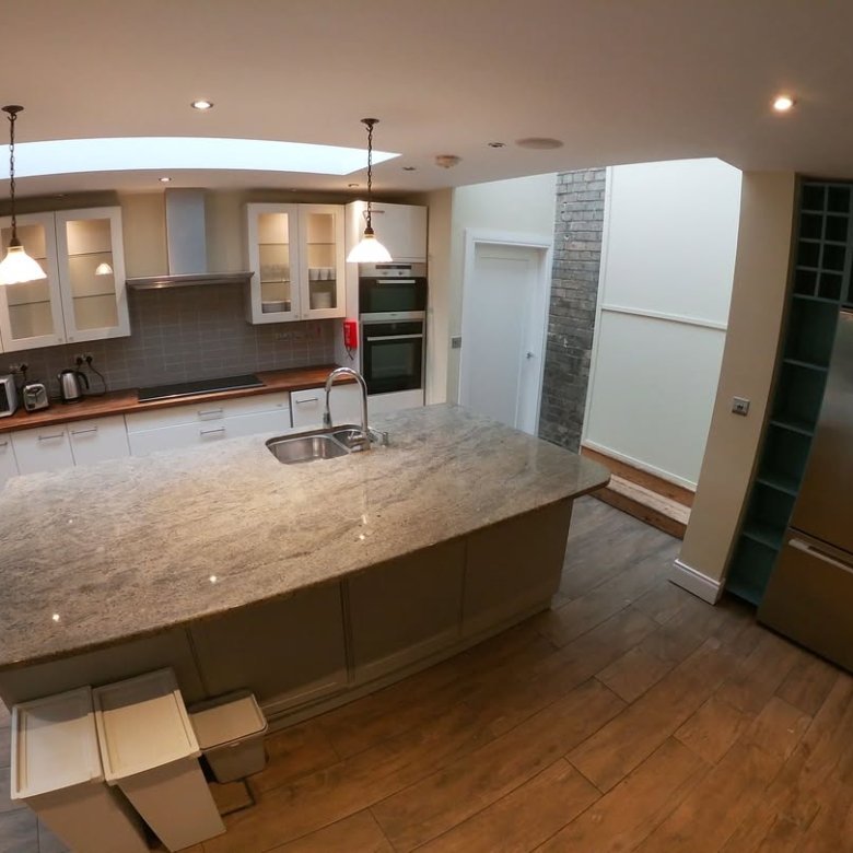 Modern kitchen with island, stainless steel appliances, and light wood floors.