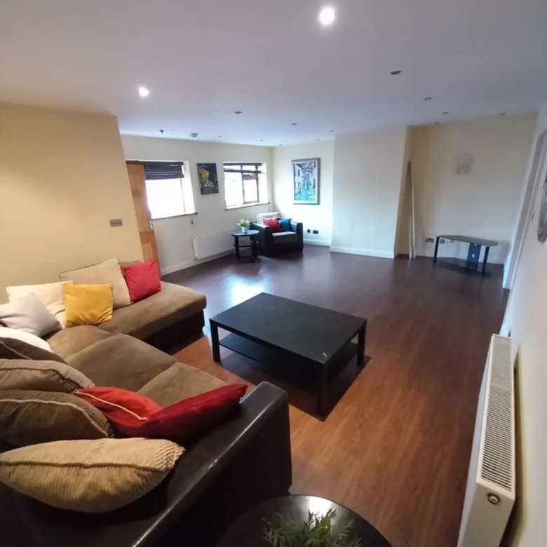 Spacious living room with brown sectional sofa, dark wood floors, and modern decor.