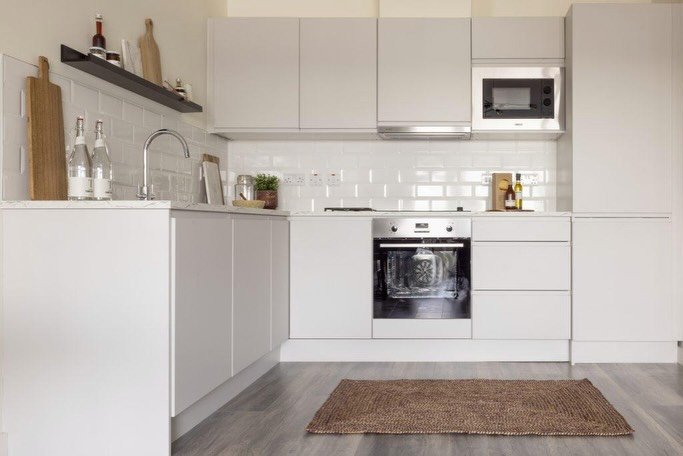 Modern kitchen with white cabinets, subway tile, stainless steel oven and microwave.