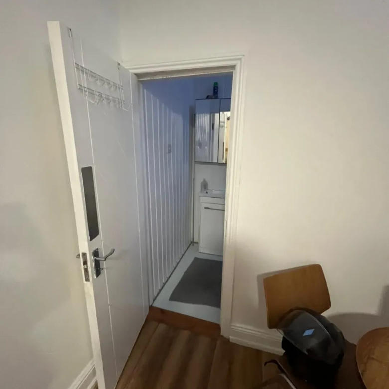 Open white door leading to small bathroom with white fixtures.