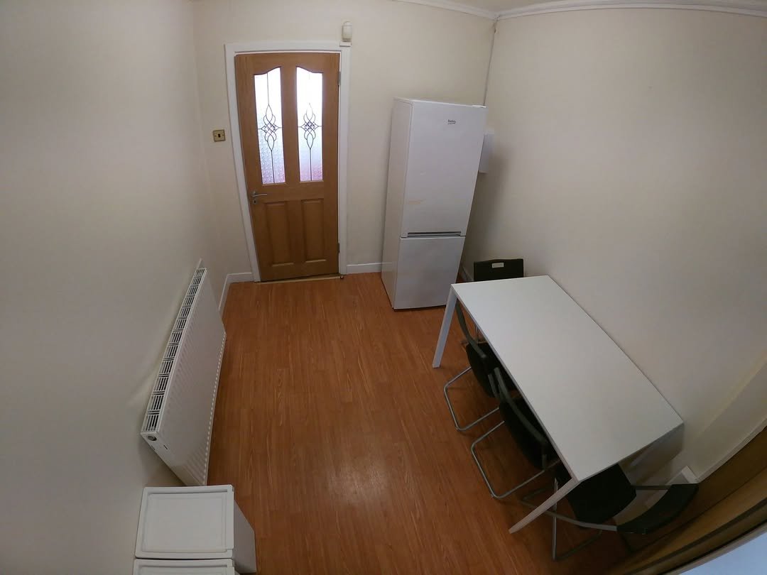 Small apartment kitchen with fridge, table, chairs, and radiator.