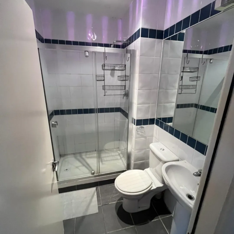 Small bathroom with shower, toilet, sink, and gray tile floor.