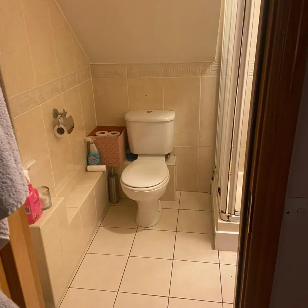 Compact bathroom with toilet, tile walls, and shower stall. Neutral color scheme.