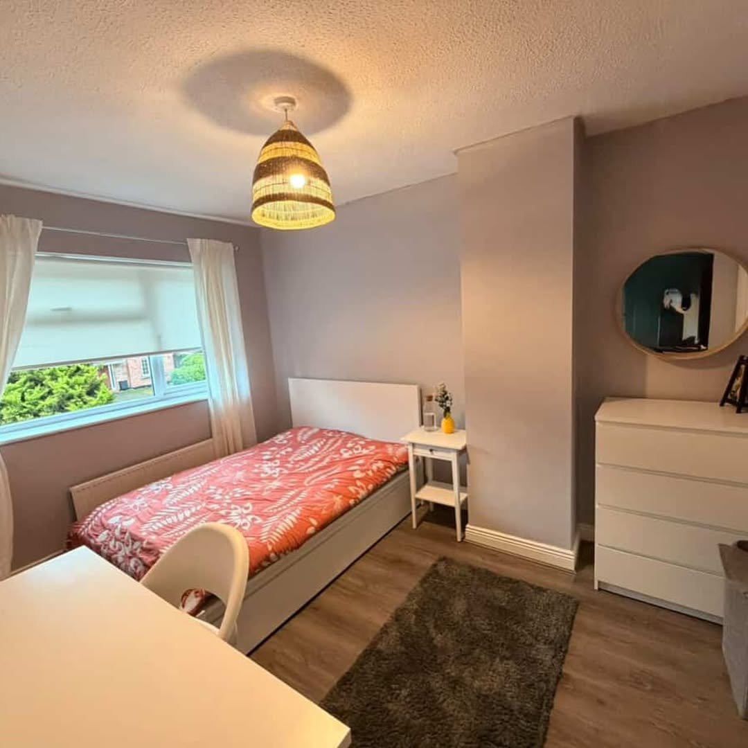 Cozy bedroom with single bed, desk, and modern decor. Natural light from window.