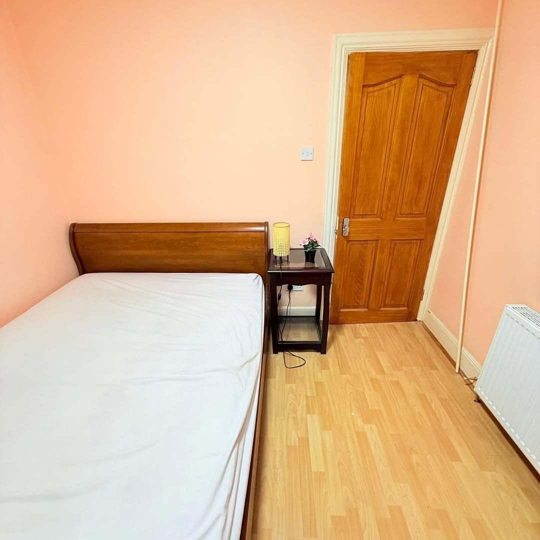 Small bedroom with single bed, nightstand, and wooden door.