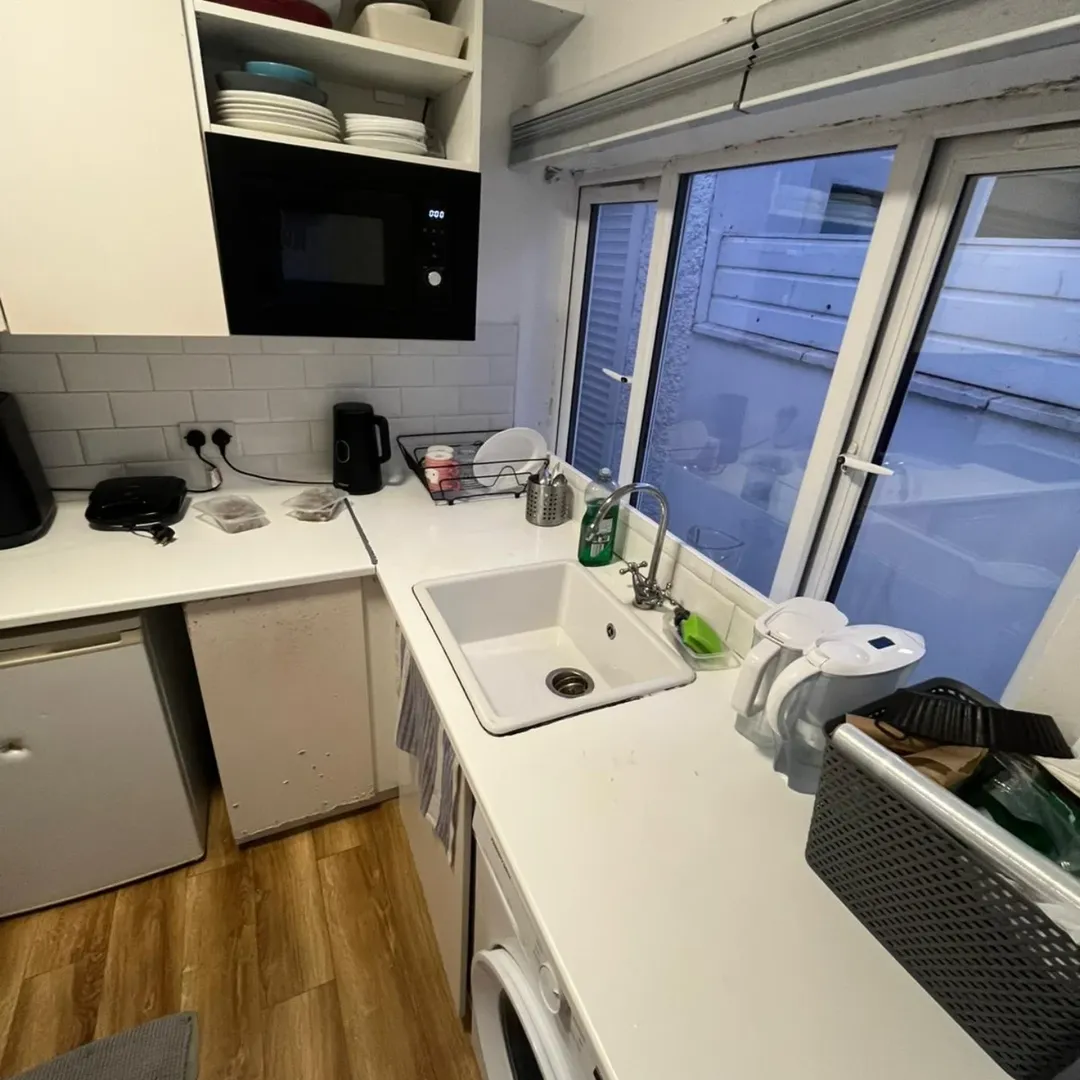 Small kitchen with white cabinets, sink, and window. Compact and functional design.