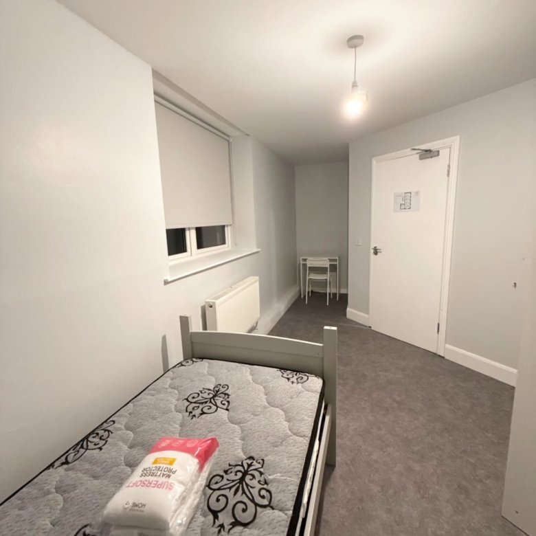 Small, modern dorm room with a single bed and desk area.